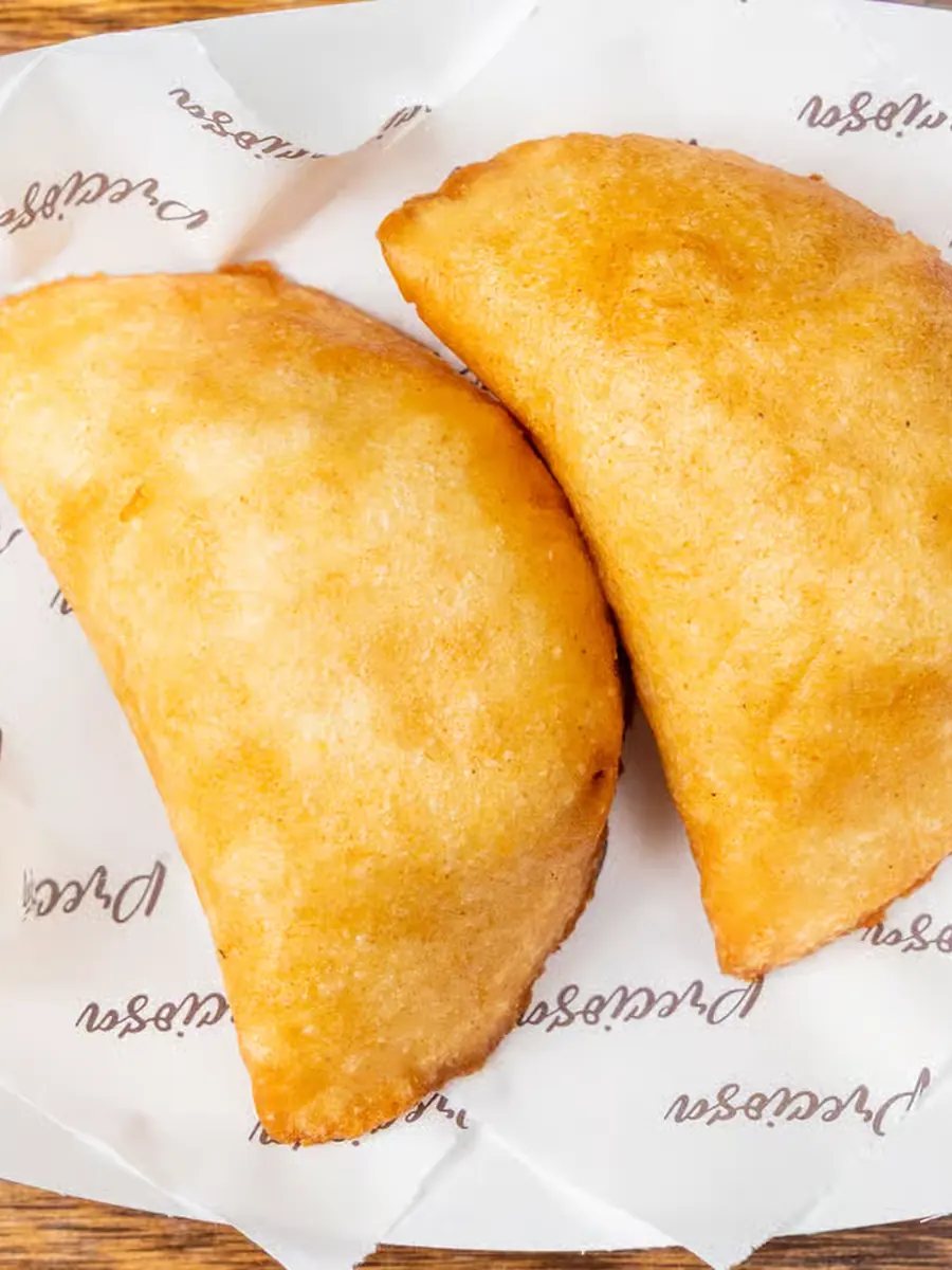 Dos empanadas fritas recién hechas sobre papel de Preciosa