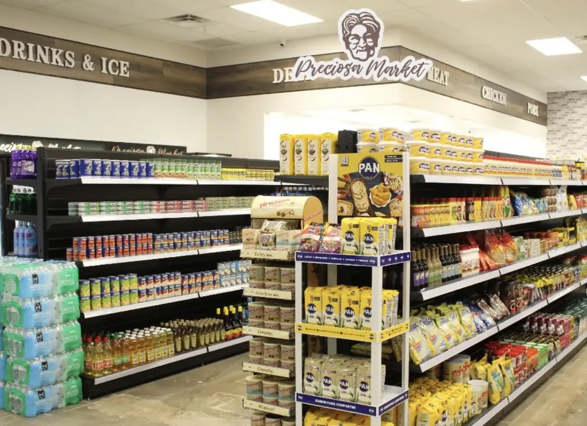 Pasillo del mercado con Harina PAN y productos venezolanos bajo el letrero de Preciosa Market