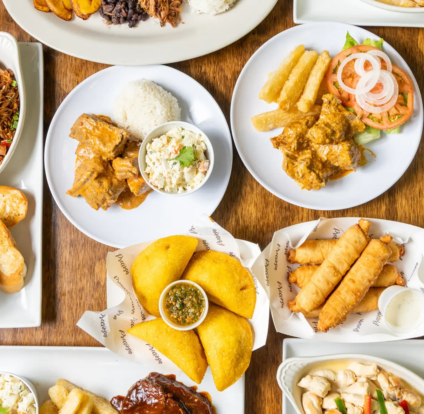 Mesa servida con empanadas, tequeños, pabellón criollo, arroz y otros platos venezolanos de Preciosa Market
